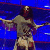 a woman with long hair is dancing on a stage in front of a pink background