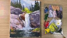 a painting of a waterfall is next to a palette