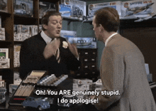 two men are talking in a store with one saying oh you are genuinely stupid i do apologise