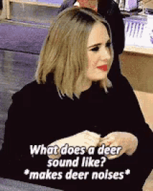 a woman is sitting at a table talking about what does a deer sound like making deer noises .