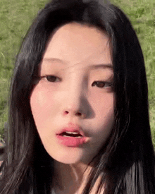 a close up of a young woman 's face with long black hair and a pink lip .