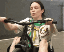 a woman is riding a bicycle with the letter j on her shirt