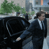 a man in a suit and tie is getting out of a car that says cougar
