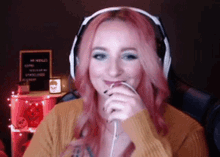 a woman with pink hair is wearing headphones and smiling while sitting in a chair .