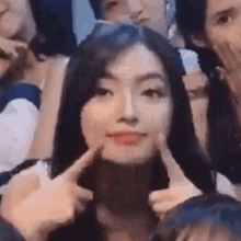 a group of people are posing for a picture and one of them is making a face with her hands .