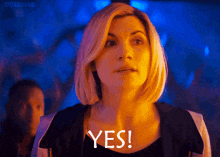 a woman with blonde hair is saying yes in a dark room