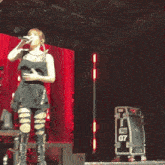 a woman singing into a microphone in front of a fragile box