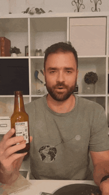 a man in a green shirt is holding a bottle of pilsner beer