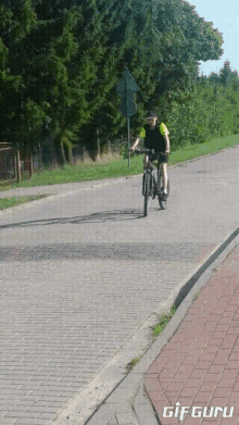 a man is riding a bike down a brick road with the words gif guru on the bottom
