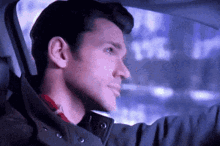 a man in a jacket is driving a car at night .