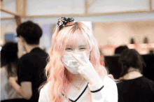 a girl with pink hair is wearing a face mask and giving the peace sign