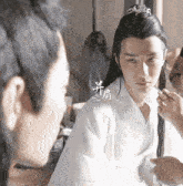 a man in a white robe is looking at another man in a mirror
