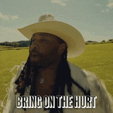 a man in a cowboy hat is standing in a field with the words bring on the hurt below him