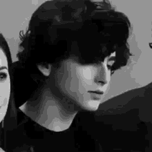 a black and white photo of a young man standing next to a woman in a room .
