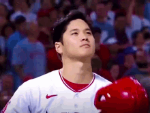 a baseball player wearing a nike jersey is holding a red helmet .