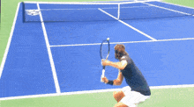 a man is holding a tennis racquet on a blue tennis court