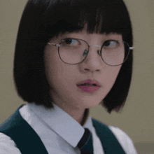 a girl wearing glasses and a white shirt looks at the camera