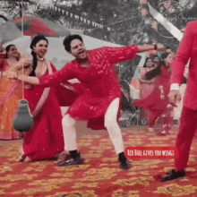 a man in a red suit is dancing in front of a crowd of people .