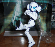 a white robot with a blue eye is standing in front of a box that says pp