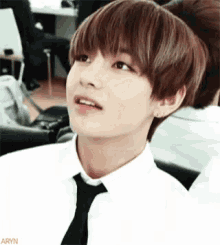 a close up of a young man wearing a white shirt and black tie .