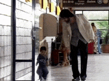 a man carrying a suitcase walks down a hallway with a sign that says b1-810 on it