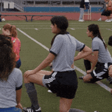 a group of female soccer players stretching on a field