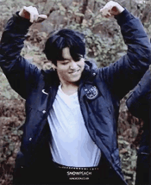 a young man in a black jacket is flexing his muscles