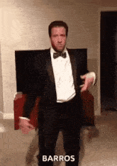 a man in a tuxedo and bow tie is dancing in front of a television .