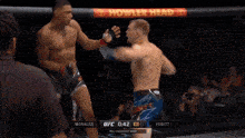 two men are fighting in a ufc ring with a toyo tires advertisement on the wall