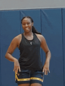 a woman in a black tank top and blue shorts with the word wnba on them