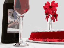 a bottle of wine next to a glass and a cake with red frosting