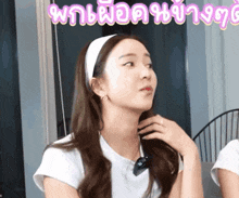 a woman wearing a white headband is sitting in front of a sign that says ' thailand ' on it