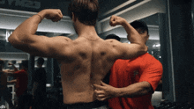 a man is flexing his muscles in front of a sign that says gym 23