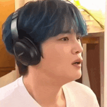 a young man with blue hair is wearing bose headphones .