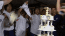 a group of people are standing around a cake with a crown on it