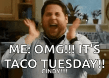 a man in a tie is screaming in a kitchen while holding his hands in the air .