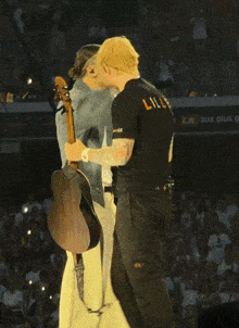 a man wearing a lille t-shirt is holding a guitar and singing into a microphone