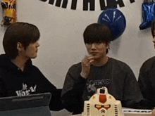 a group of young men are sitting at a table with balloons hanging on the wall .