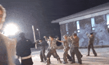 a group of young men are dancing in front of a building