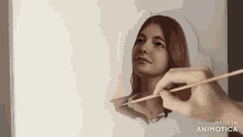 a person is painting a woman 's face and the words made in animotica are visible