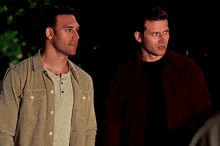 two men are standing next to each other and looking at each other .