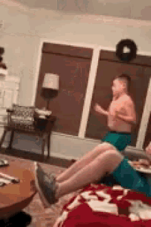 two boys are playing in a living room with a christmas wreath on the wall behind them .