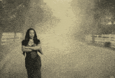 a black and white photo of a woman standing in the fog
