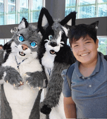 a boy in a blue shirt is standing next to two furry animals