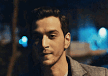a man with a beard is wearing a grey jacket