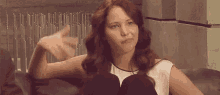 a woman is sitting on a couch making a funny face while making a funny face .