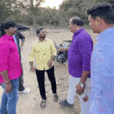 a group of men are standing around a motorcycle and talking