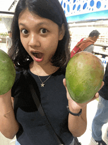 a woman is holding two large green fruits in her hands and making a funny face
