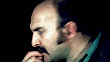 a bald man with a mustache is looking down