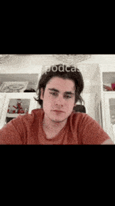 a young man in an orange t-shirt is looking at the camera with the words yo podcast written above him